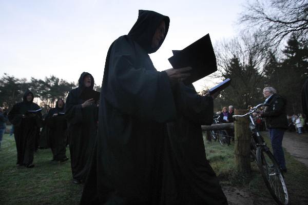 \"Overasselt: Processie en Gregoriaanse gezang van de Schola Cantorum Karolus Magnus bij de koortsboom in Sint Walrick. Bij het ochtendgloren klonk de Hymnus ad Galli cantum: de hymne bij het kraaien van de haan.\"