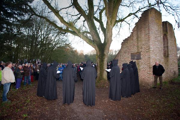 \"Overasselt: Processie en Gregoriaanse gezang van de Schola Cantorum Karolus Magnus bij de koortsboom in Sint Walrick. Bij het ochtendgloren klonk de Hymnus ad Galli cantum: de hymne bij het kraaien van de haan.\"