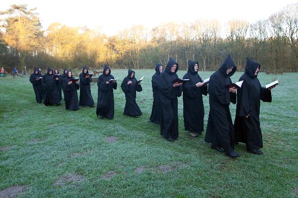 \"Overasselt: Processie en Gregoriaanse gezang van de Schola Cantorum Karolus Magnus bij de koortsboom in Sint Walrick. Bij het ochtendgloren klonk de Hymnus ad Galli cantum: de hymne bij het kraaien van de haan.\"