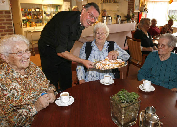 \"Pastoor Smits serveert soesjs aan bewoners bejaardenhuis St. Jan de Deo , na een dienstenveiling waarvoor de opbrengst bestemd is voor de Cliniclowns\"