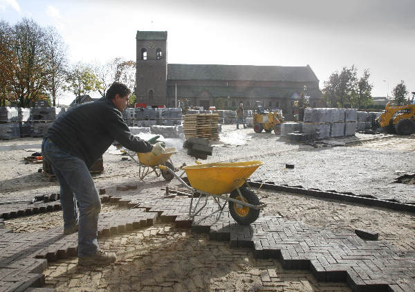 \"Centrum Breedeweg krijgt nieuw dorpshart.bestratingswerkzaamheden met dorpskerk op de achtergrond\"