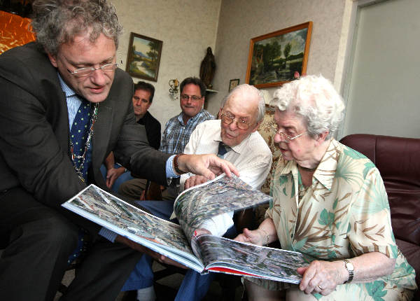 \"Familie de Bruin is 65 jaar getrouwd: burgemeester komt en bekijkt het geschenk, het boek met lchtfoto\'s van Nijmegen.\"