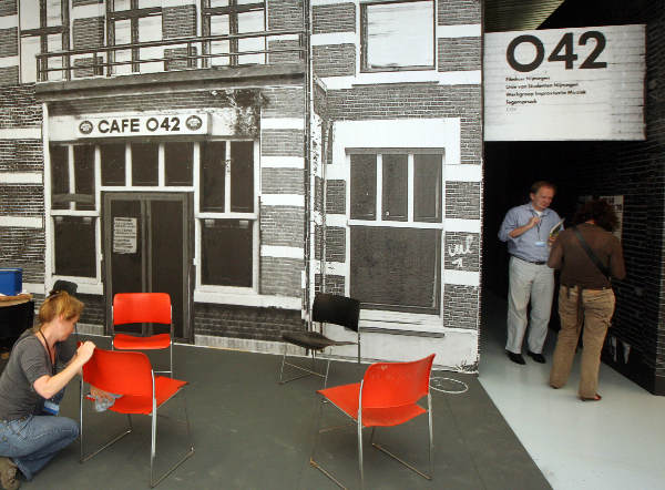 "Valkhof museum, Seventies in Nijmegen tentoonstelling met nagebouwd O 42 en Timmermans, schrijver van het boek en vroeger barman in O 42 in de deur... en de stoelen worden nog schoongemaakt"
