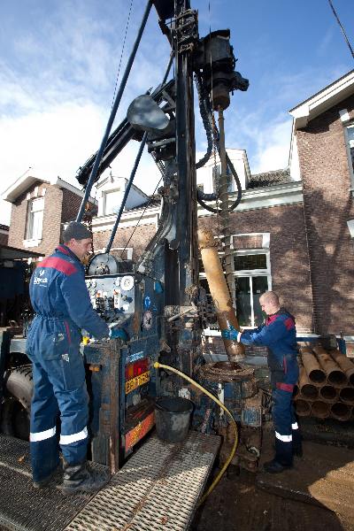 \"Slaan, boren van put in de Claas Noorduynstraat. In opdracht van de gemeente worden Nijmegen oost meerdere putten geslagen met meet apparatuur voor het rondwater. Deze put gaat 50 meter diep.Op deze plek zit het grondwater op 30 meter.\"