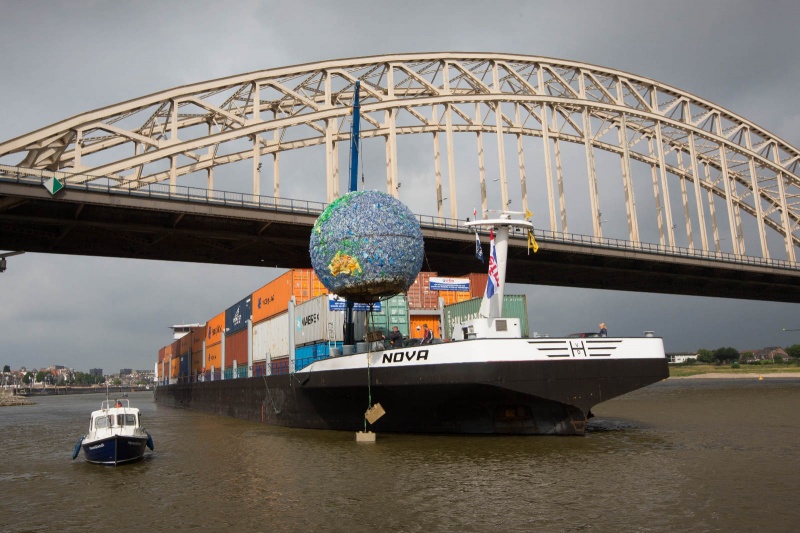 De Wereldbol die ruim 14 dagen in de Waal bij de Waalbrug gelegen heeft, wordt op een 115 meter lang containerschip getakeld. De bol, gemaakt van 6000 flesjes zwerfvuil maakt een reis door Nederland om aandacht te vragen voor zwerfvuil. Gaat nu naar Dordrecht. Nijmegen, 31-7-2013 . dgfoto.