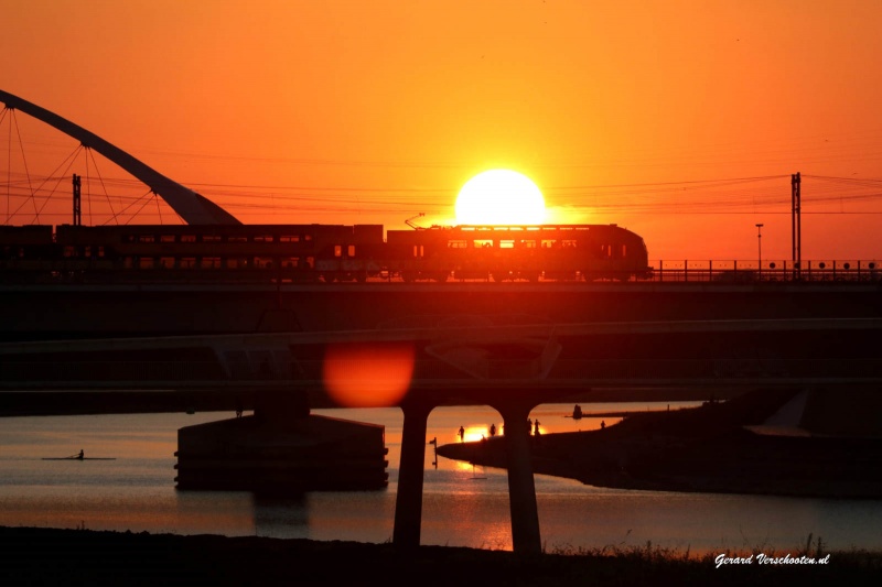 Ondergaande zon met brug, trein, centrale. Nijmegen, 26-8-2016 .