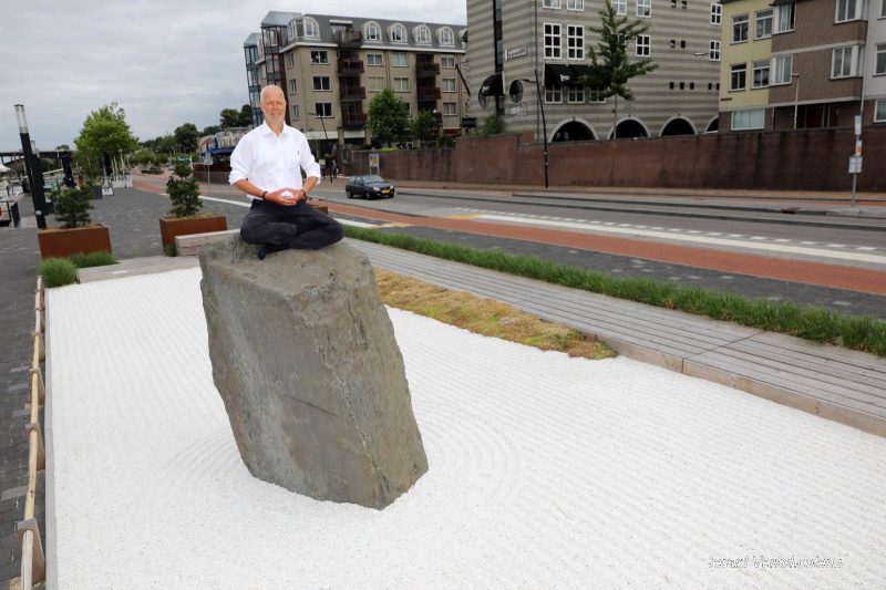 Rients Ritskes, oprichter van Zen-centrum, harkend in de zen-tuin aan de Waalkade (schuin tegenover de Grotestraat). Verhaal is: zentuin mag langer blijven ?n de tuin blijkt 'hufterproof'' te zijn (dus geen vandalisme of hondenuitlaatplaats. Nijmegen, 12-6-2017 .