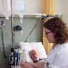 \"verpleegkundige Afbeelding van een verpleegkundige die het infuus controleert van iemand die in een ziekenhuisbed ligt. Hij is ondertussen in gesprek met de patië®´.\"